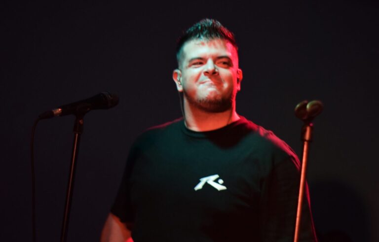 Euge Luján sonriendo en pleno show de Quiero Cumbia bajo luces rojas.