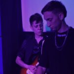 Antonella Vitanza tocando la guitarra durante un show de Quiero Cumbia bajo luces violetas.