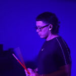 Bruno Barreto tocando percusión electrónica en vivo con Quiero Cumbia bajo luces azules