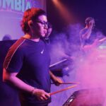 Bruno, percusionista de Quiero Cumbia, tocando el pad electrónico en vivo entre luces y humo del escenario