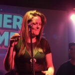 Georgina Otero cantando en vivo con el logo de Quiero Cumbia proyectado detrás