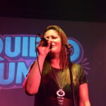 Georgina Otero cantando en vivo con el cartel de Quiero Cumbia de fondo