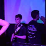 Guitarrista de Quiero Cumbia sonriendo en el escenario durante un show en vivo